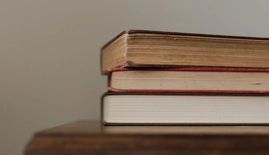 Multiple books stacked on a wooden table