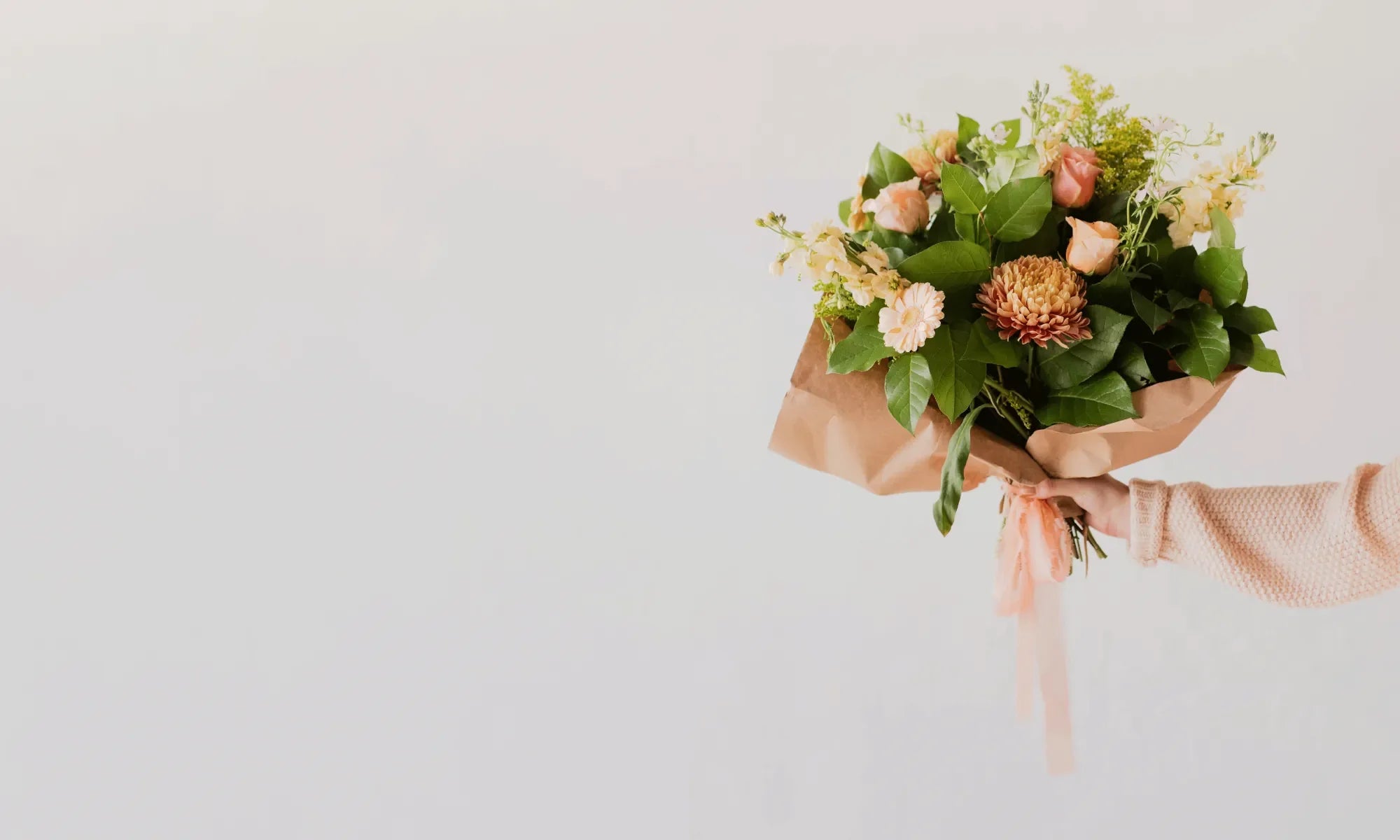 A woman holding a bouquet of flowers in a brown wrap