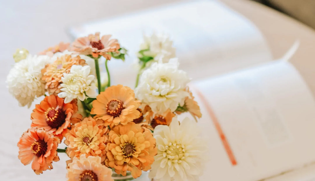 Orange and white flowers bunched together overlooking an open book
