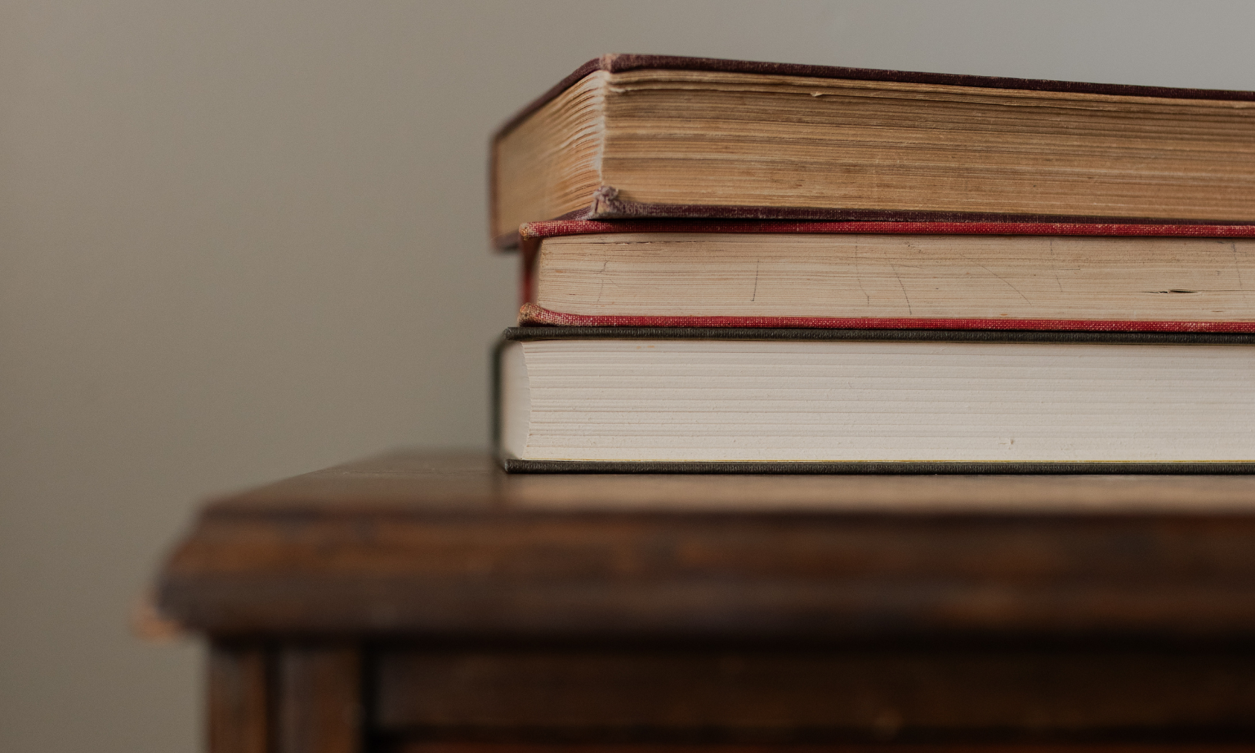 Multiple books stacked on a wooden table