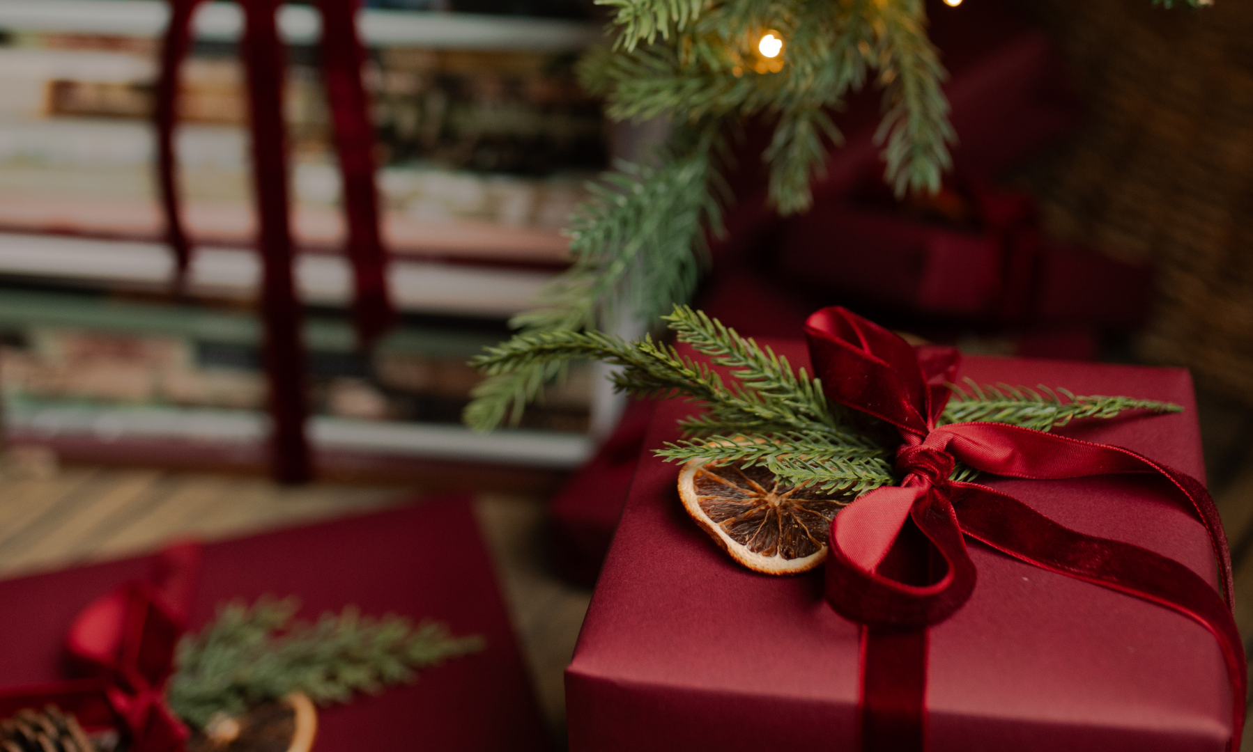 A red wrapped gift with red ribbons near a stack of bible studies