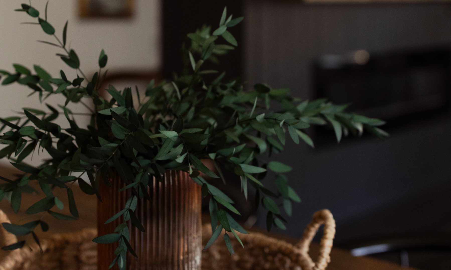 A potted plant in a wicker basket on a wooden table