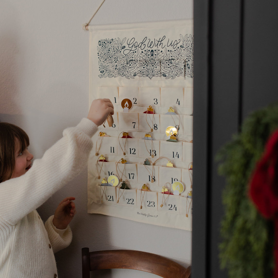 A girl putting a hanging decoration in a hanging calendar on the wall