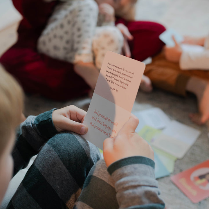 A kid holding a Advent Card for Little Hearts reading the text side