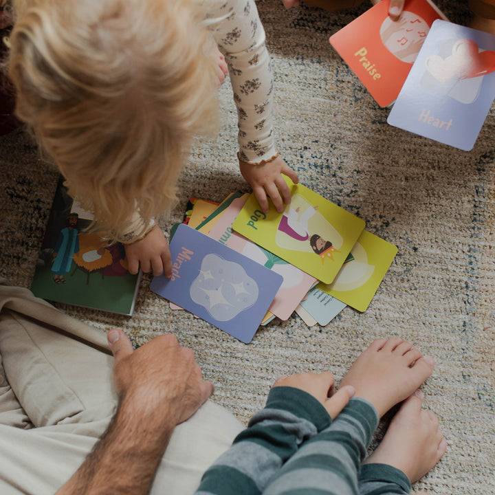 Multiple kids holding the Advent Cards for Little Hearts on a carpet