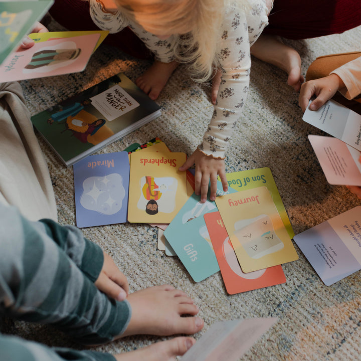 Multiple Kids touching multiple Advent Cards for Little Hearts that are laying on a carpet