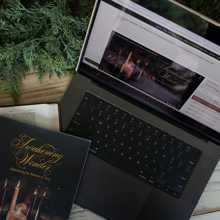 Awakening Wonder Group Leader Guide loaded on a laptop on a light wooden table next to some greenery and a Awakening Wonder bible study resting on the palm rest of the laptop