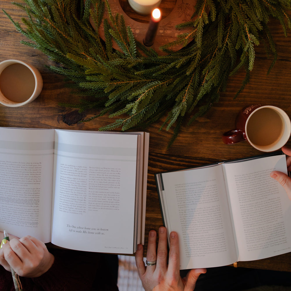 The Awakening Wonder Woman and Mens study open side by side on a wooden table with some greenery and coffee cups nearby