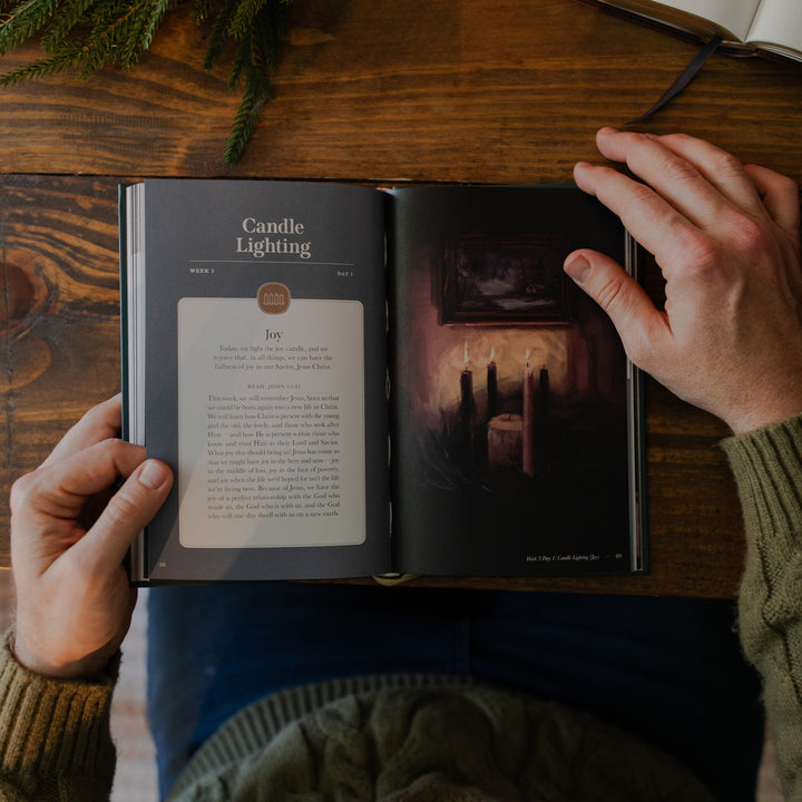 A man's hands holding the Awakening Wonder study open to the Week 3 Day 1 candle lighting page