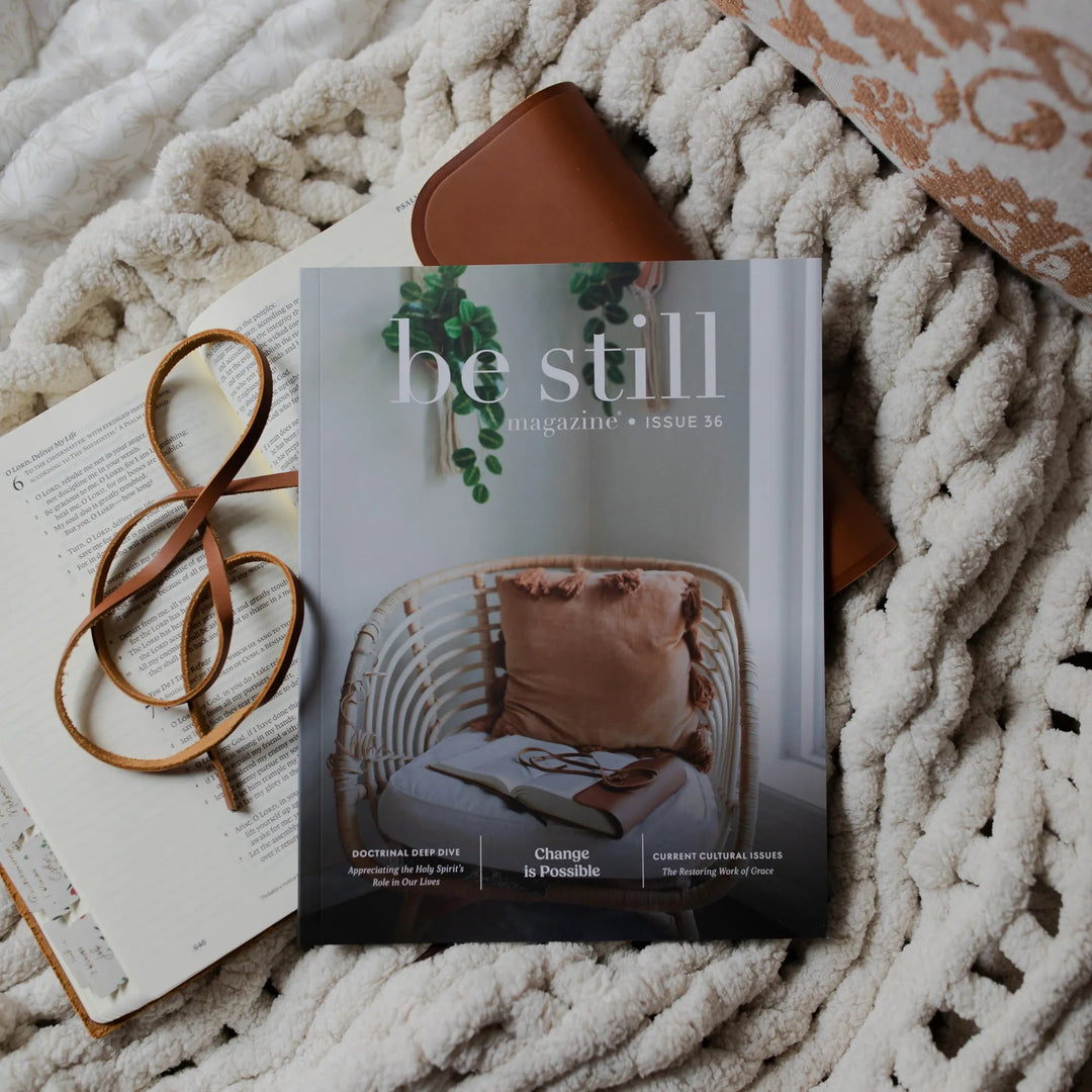 Be Still Issue 36 Magazine laying on an open bible on a white knitted blanket