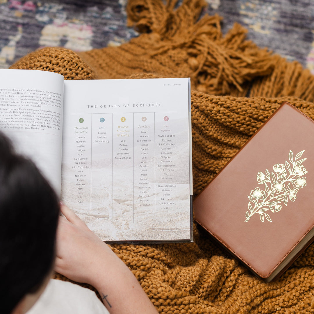 Woman looking through pages of handbook with bible next to her