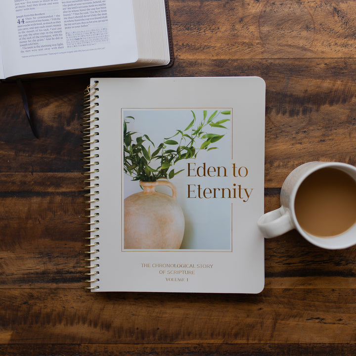 Eden to Eternity Volume 1 spiral on a wooden table next to a coffee cup and an open bible