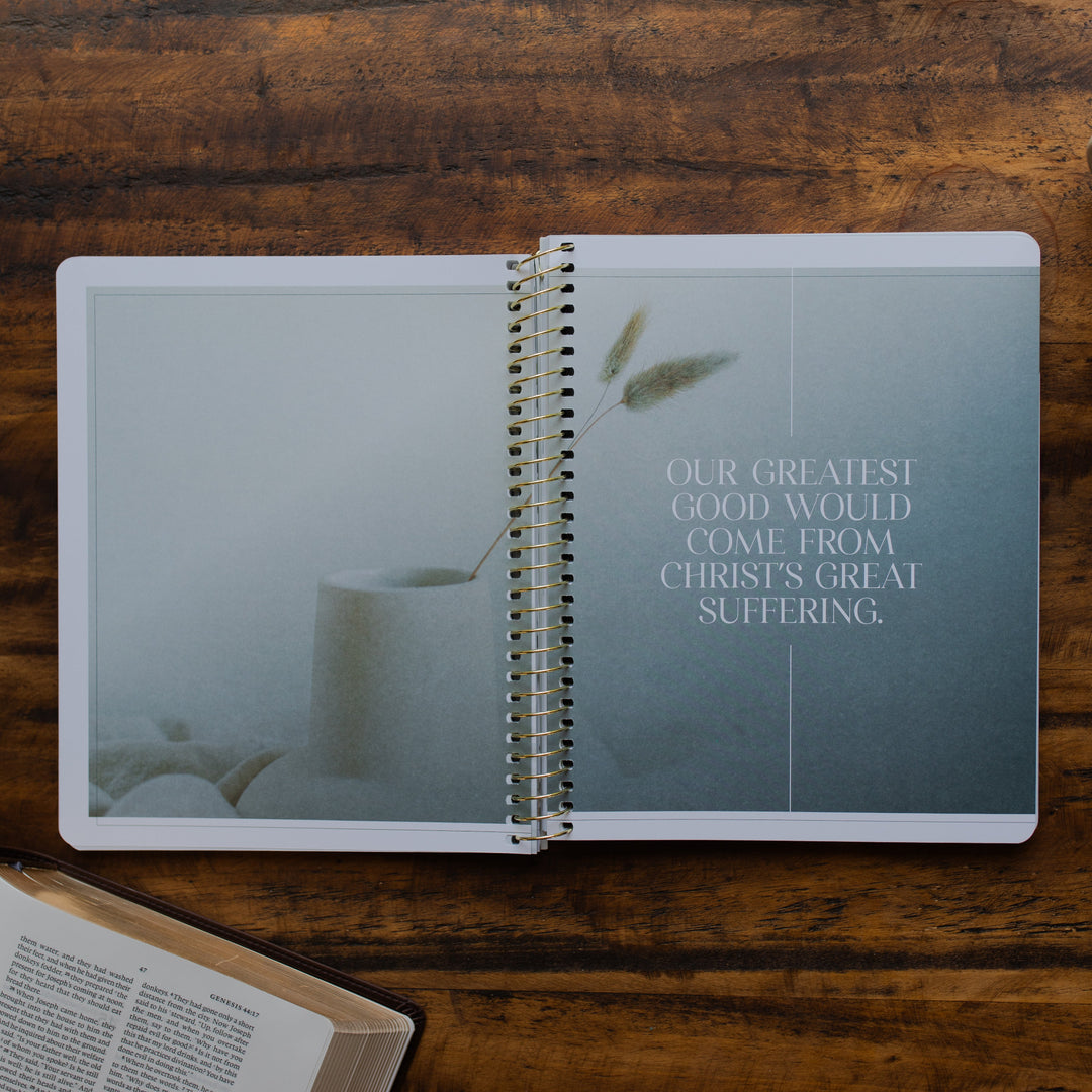 Eden to Eternity Volume 1 spiral opened to a devotional quote on a wooden table next an open bible