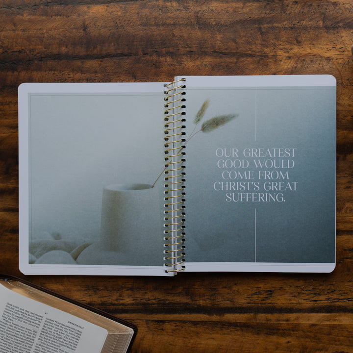 Eden to Eternity Volume 1 spiral opened to a devotional quote on a wooden table next an open bible