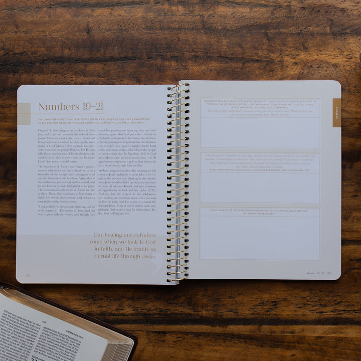 Eden to Eternity Volume 1 spiral opened to the reflections page for Numbers 19-21 page on a wooden table next an open bible