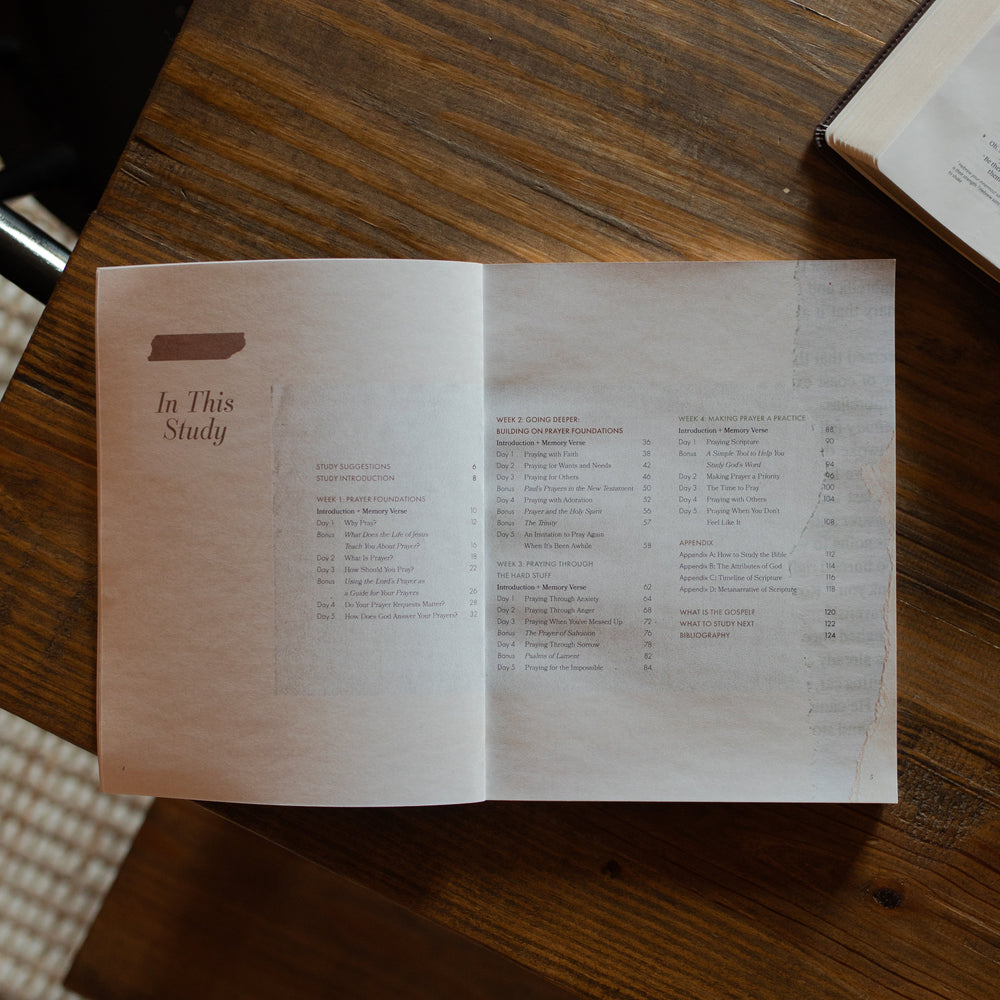The Pray study opened to the table of contents on a wooden table near an open bible