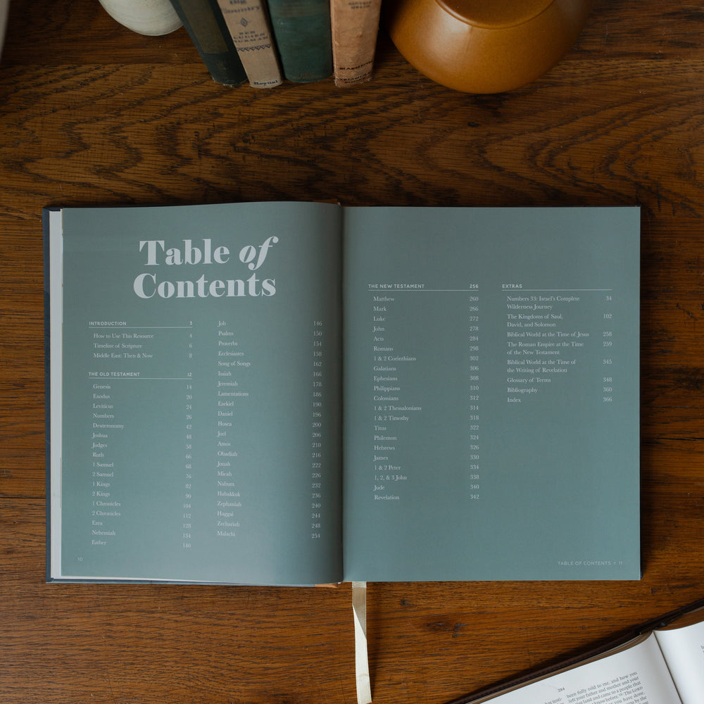 The Bible Maps Handbook opened to the table of contents page on a wooden table near an open bible