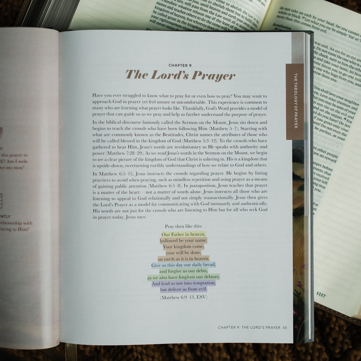 The Prayer Handbook opened to the The Lord's Prayer on Chapter 9 on an open bible on a brown knitted blanket