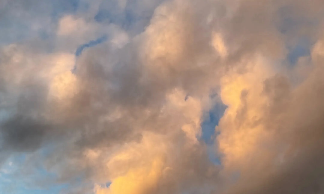 White clouds on a sunny sky with some dark smoke like clouds on the left