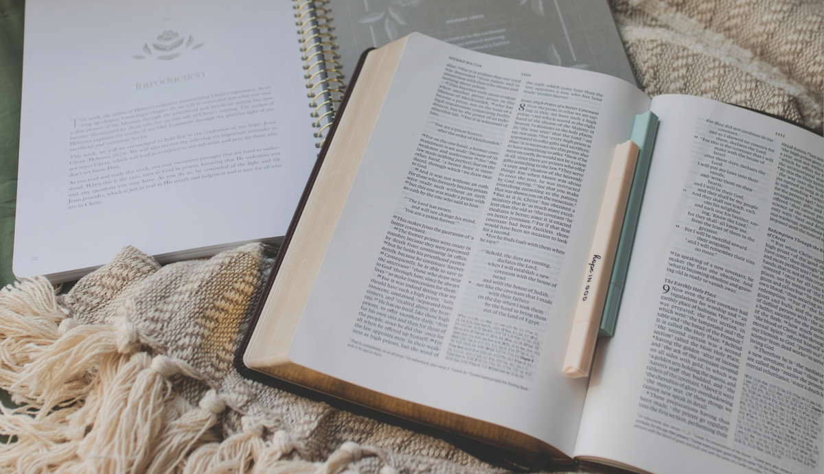 A highlighter in the middle of an open bible near an open spiral study