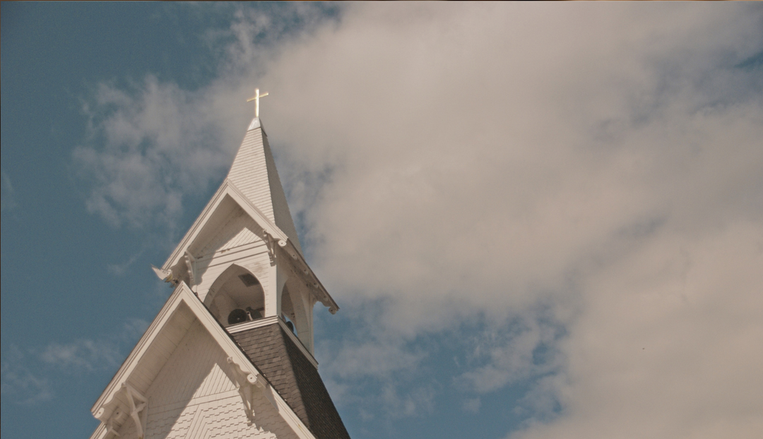 The top section of a chapel with a clear sky in the background with some light clouds