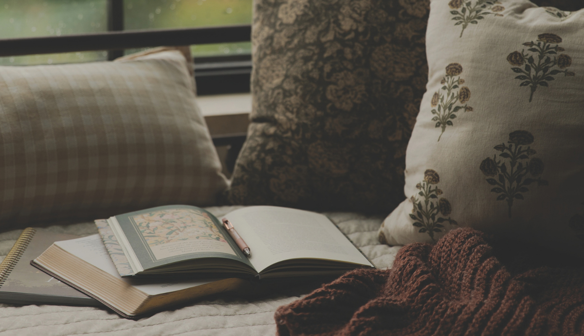 An open bible study and an open bible on a blanket near multiple pillows