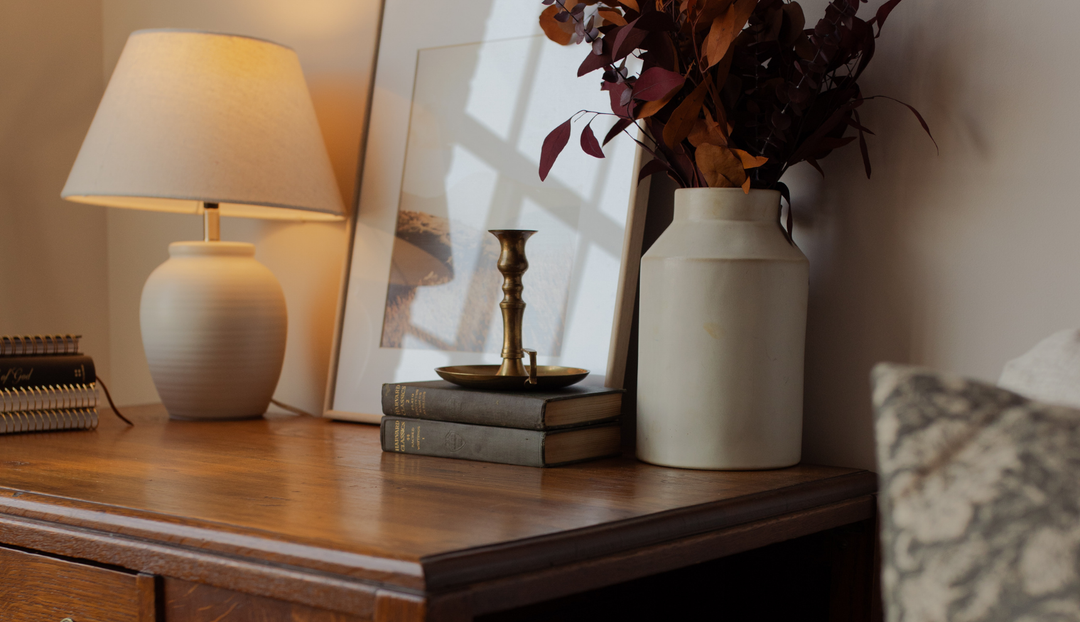 A wooden desk with some books and a white vase on it
