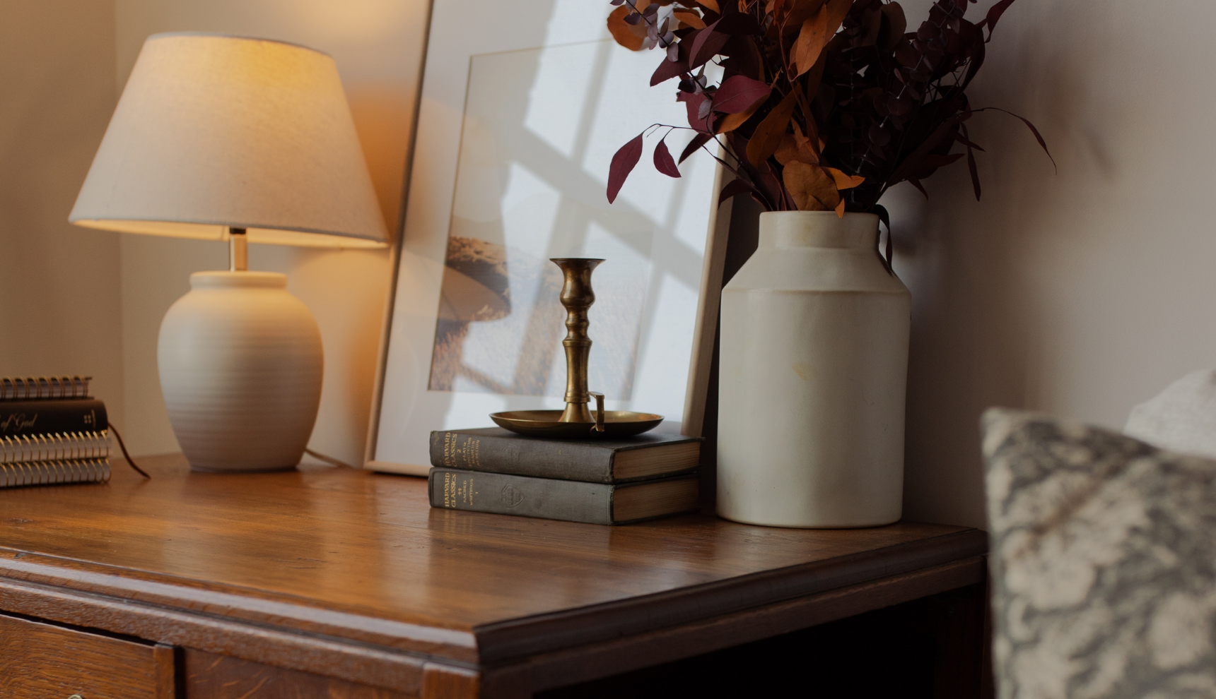 A wooden desk with some books and a white vase on it