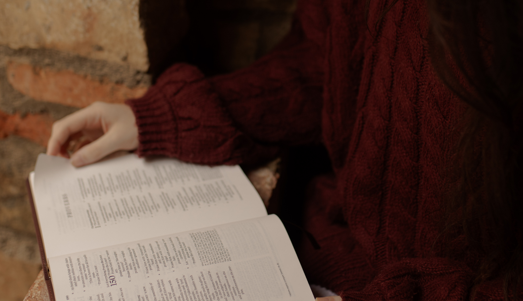 A woman with a red sweater reading an open bible