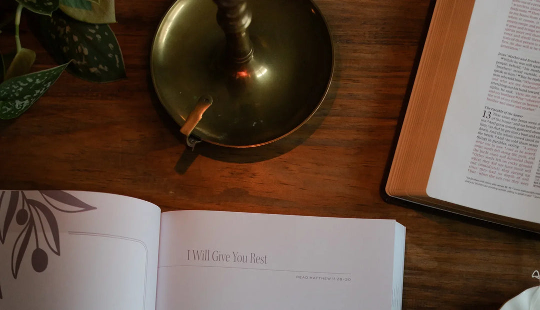 Daily Grace Bible study opened on a wooden table next to an open bible and an oil lamp