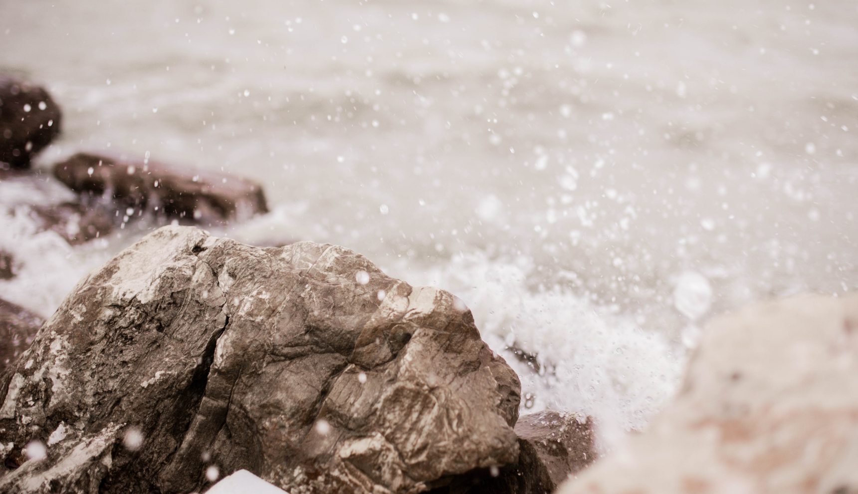 Waves crashing over multiple rocks on a shoreline