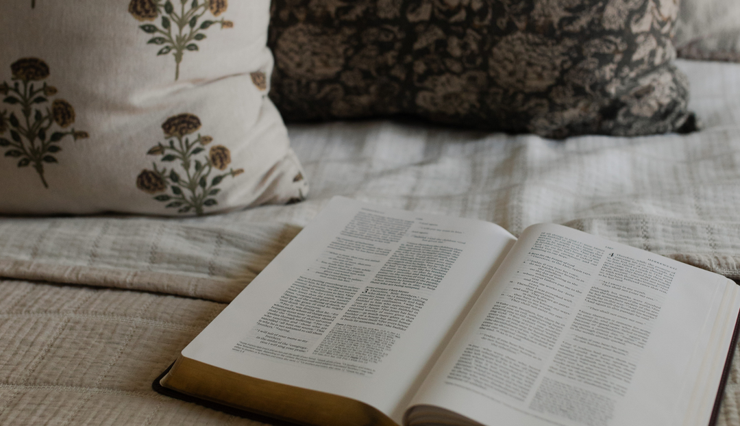 An open bible on a blanket next to some blankets