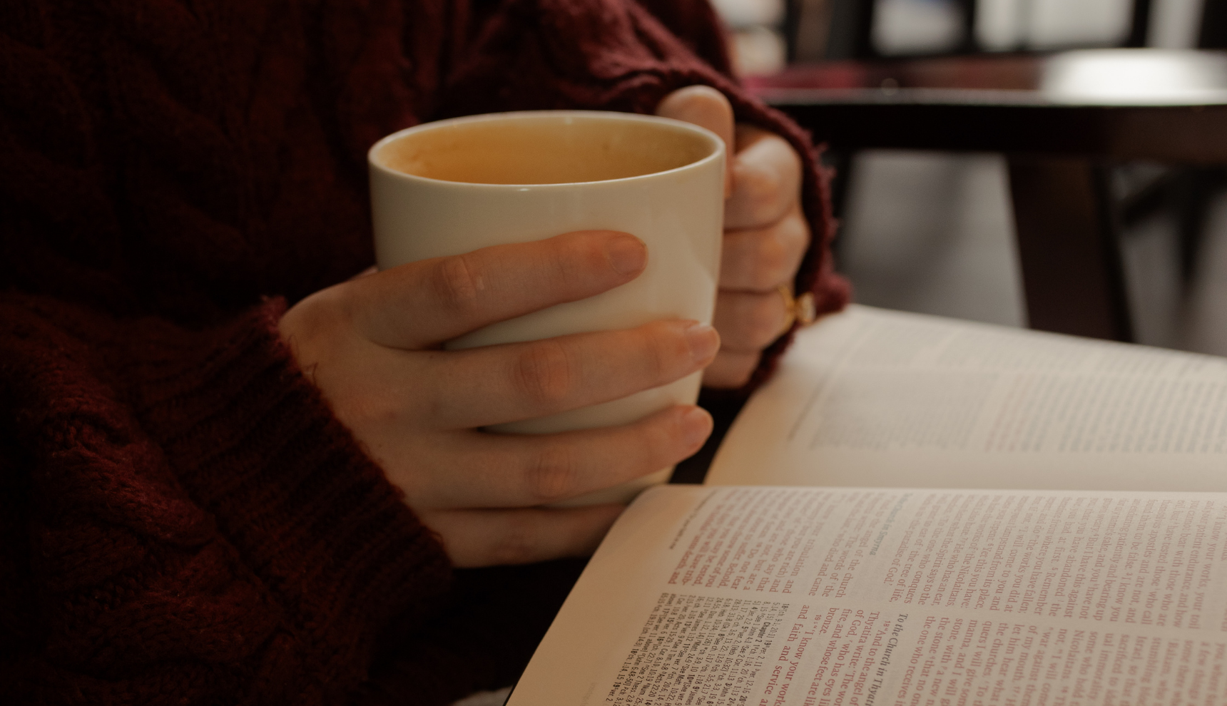 A woman holding a coffee cup near an open bible