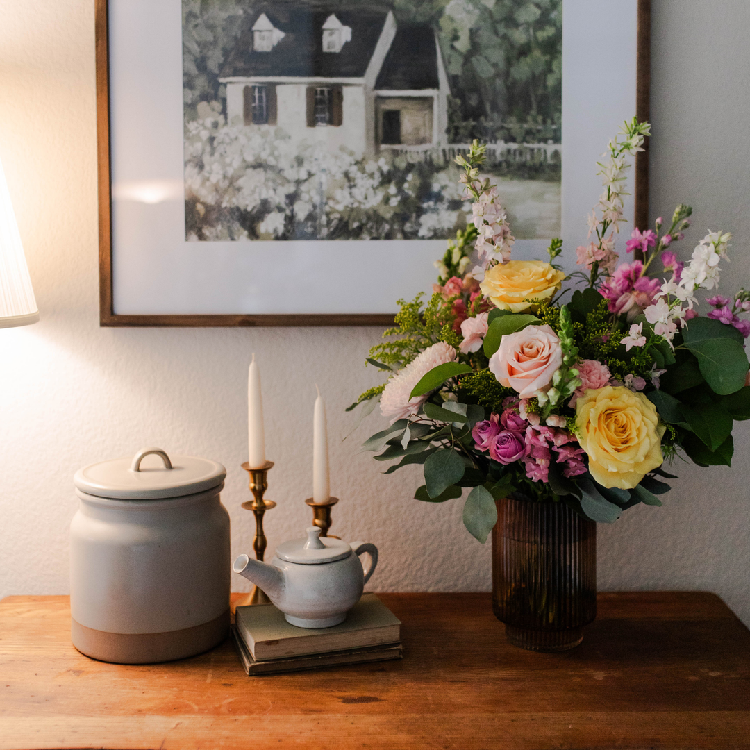 A table with some flowers and candles on it near a teapot