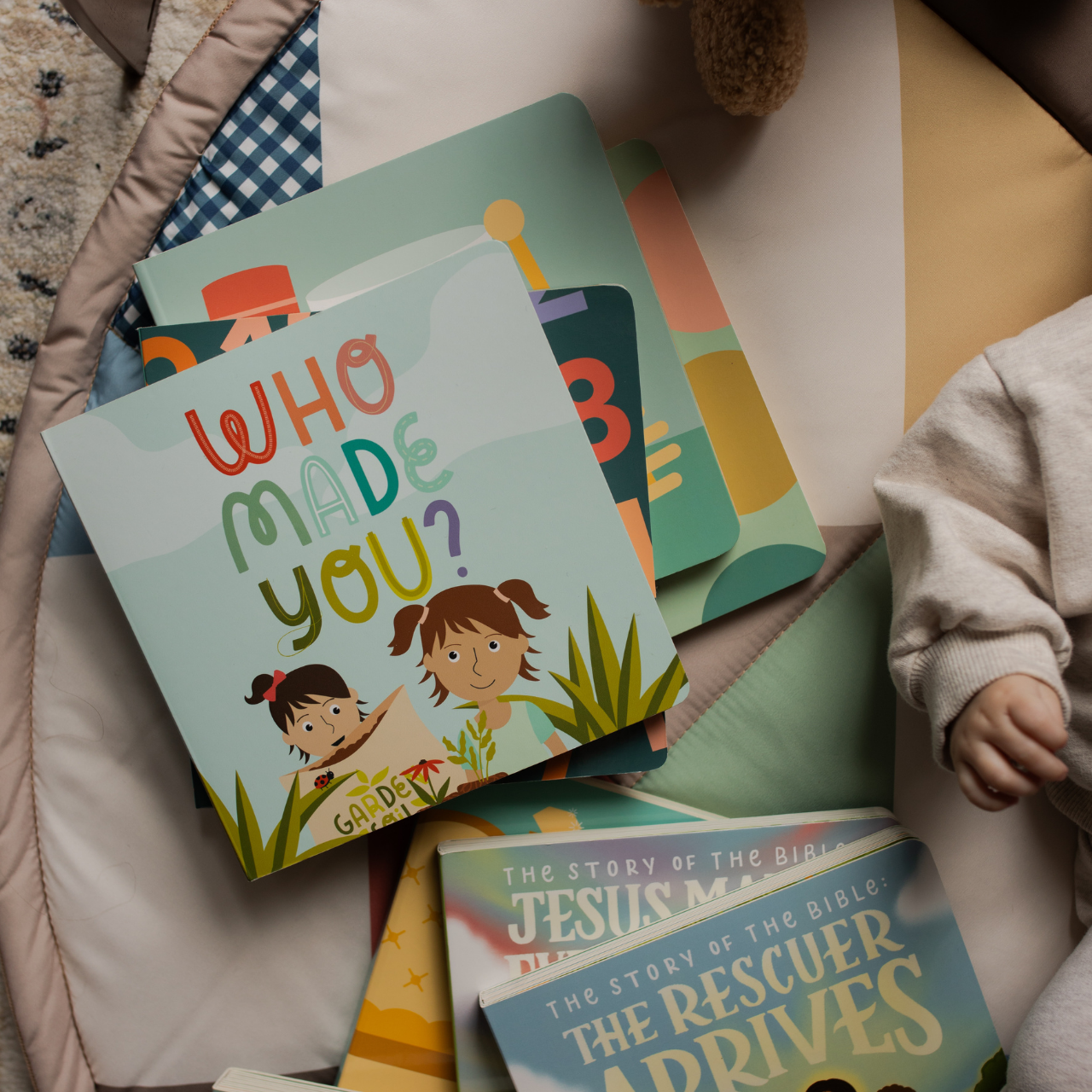 Multiple Kids books next to a baby hand