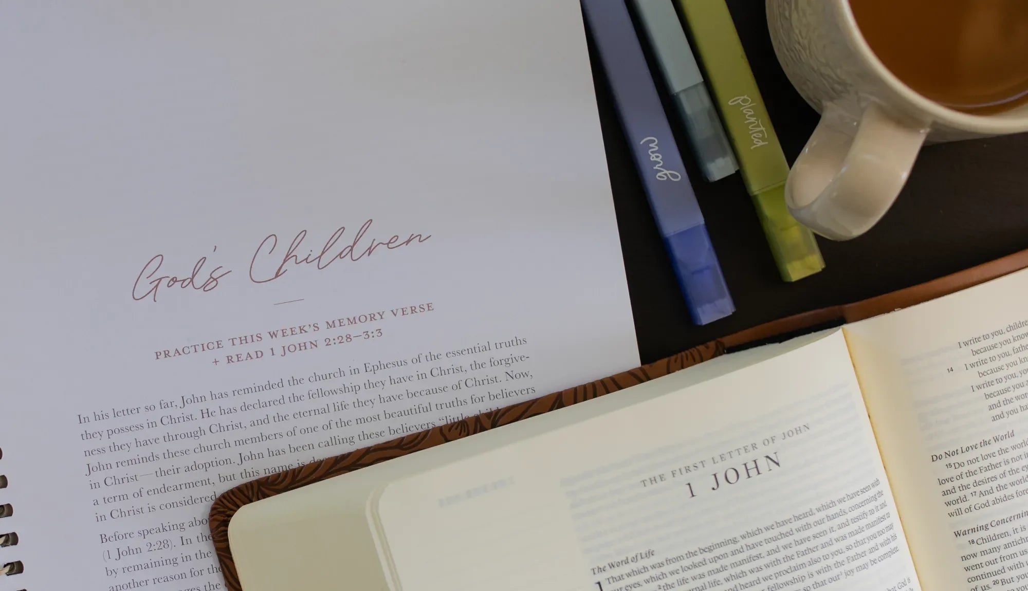 An open bible laying on a bible study and next to some Daily Grace highlighters