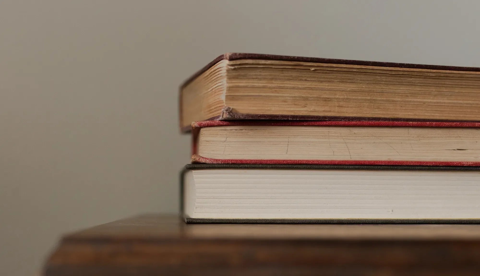 Multiple books stacked on a wooden table