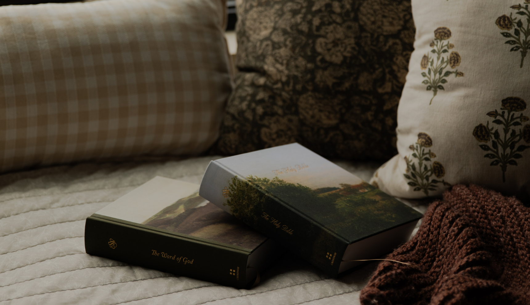 Two bibles stacked on each other on a couch near some pillows
