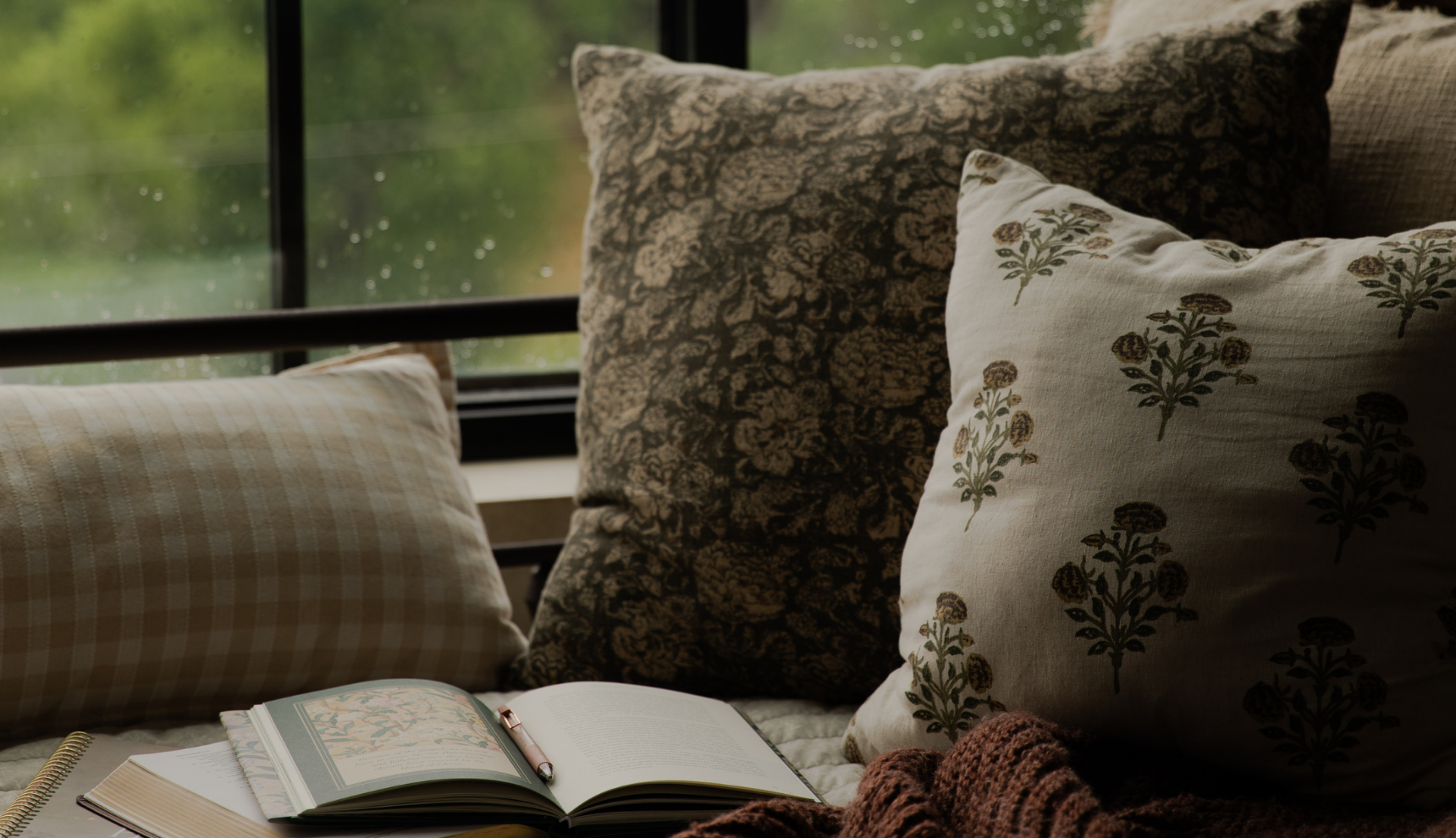 Multiple pillows next to an open study and a window