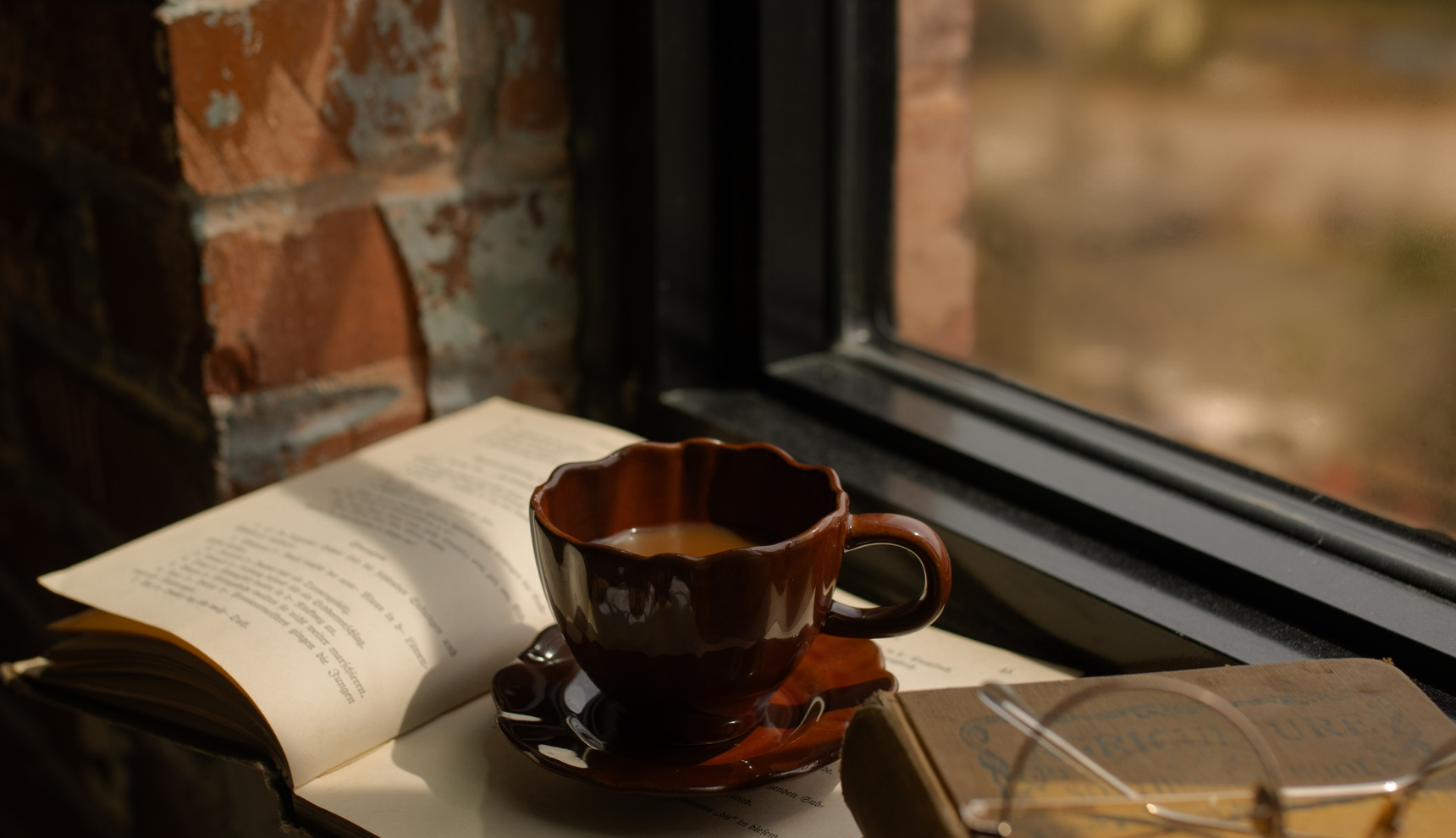 A coffee cup on an open book near a window