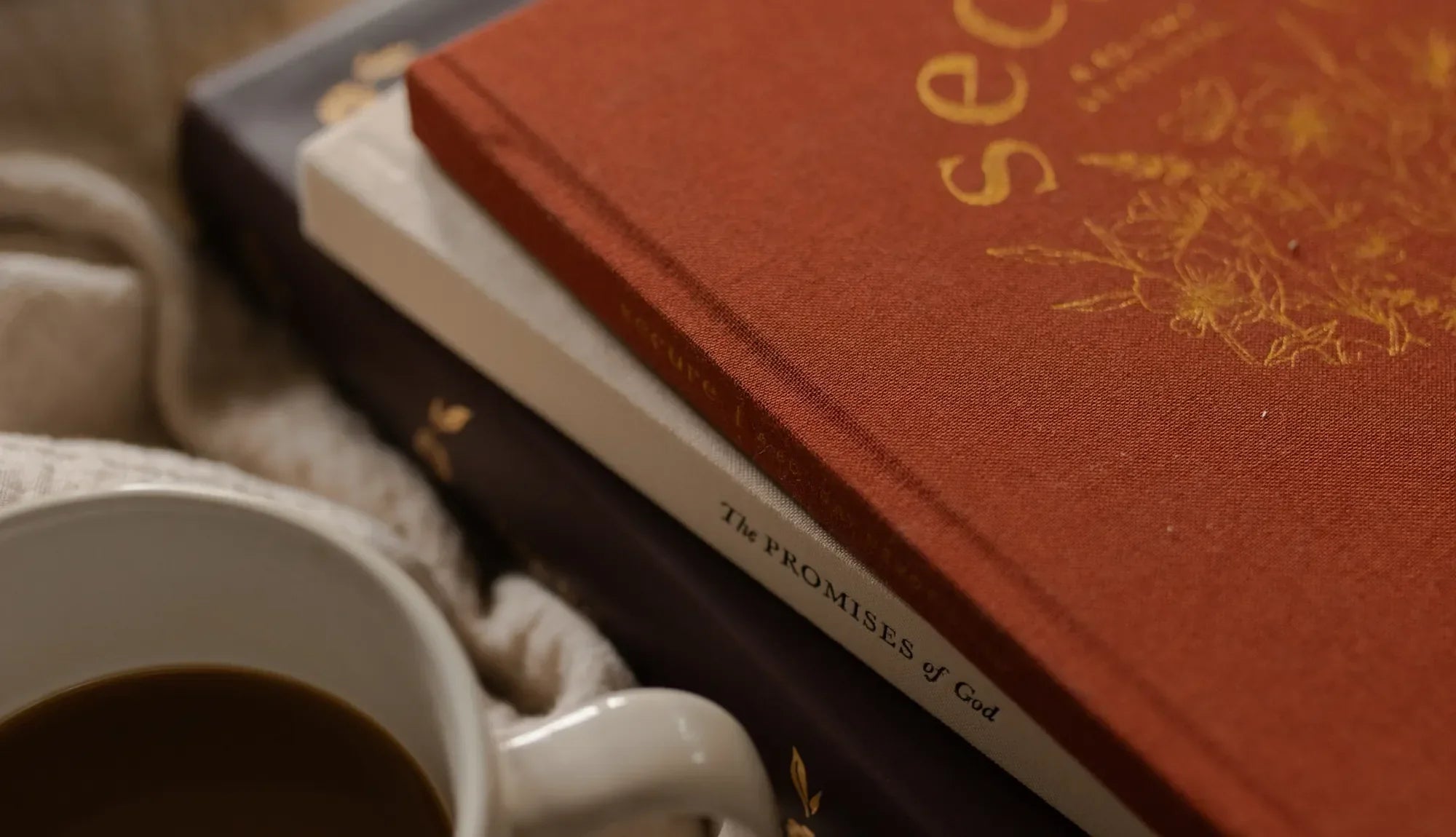 A stack of bible studies next to a coffee cup