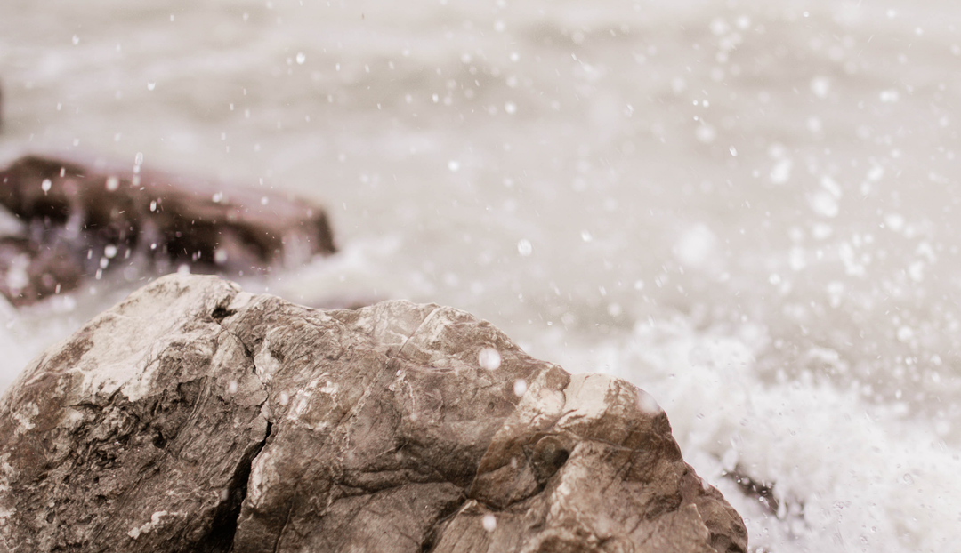 Water splashing against large gray stones