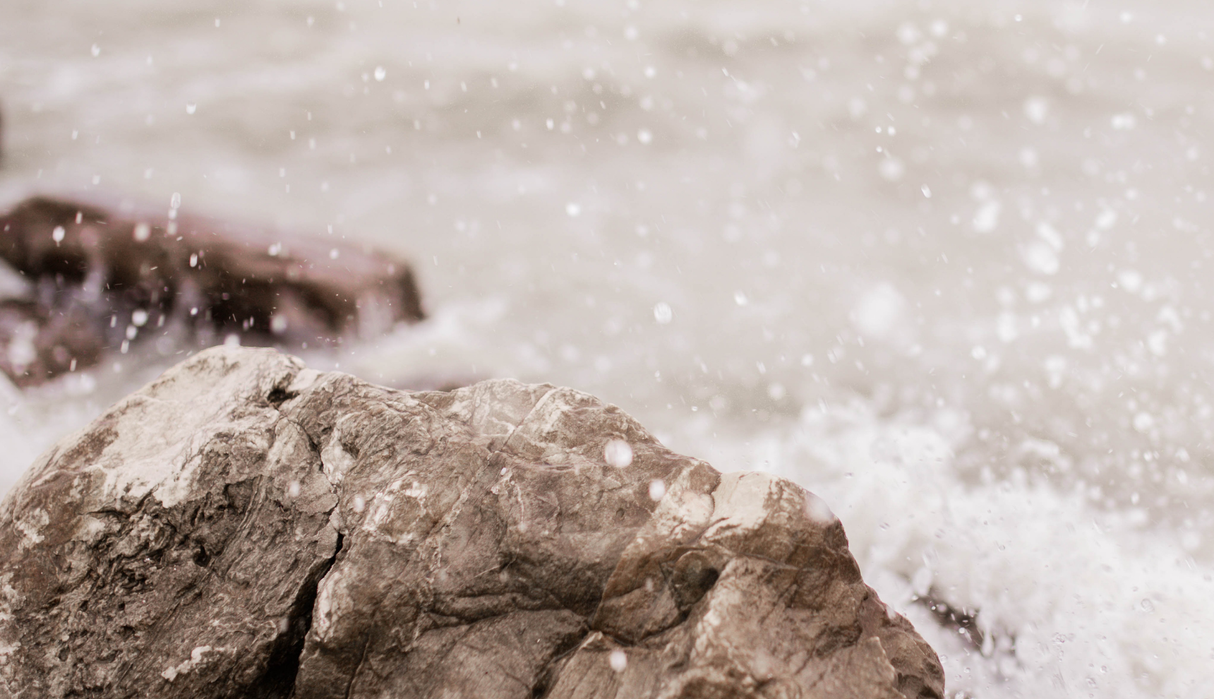 Water splashing against large gray stones