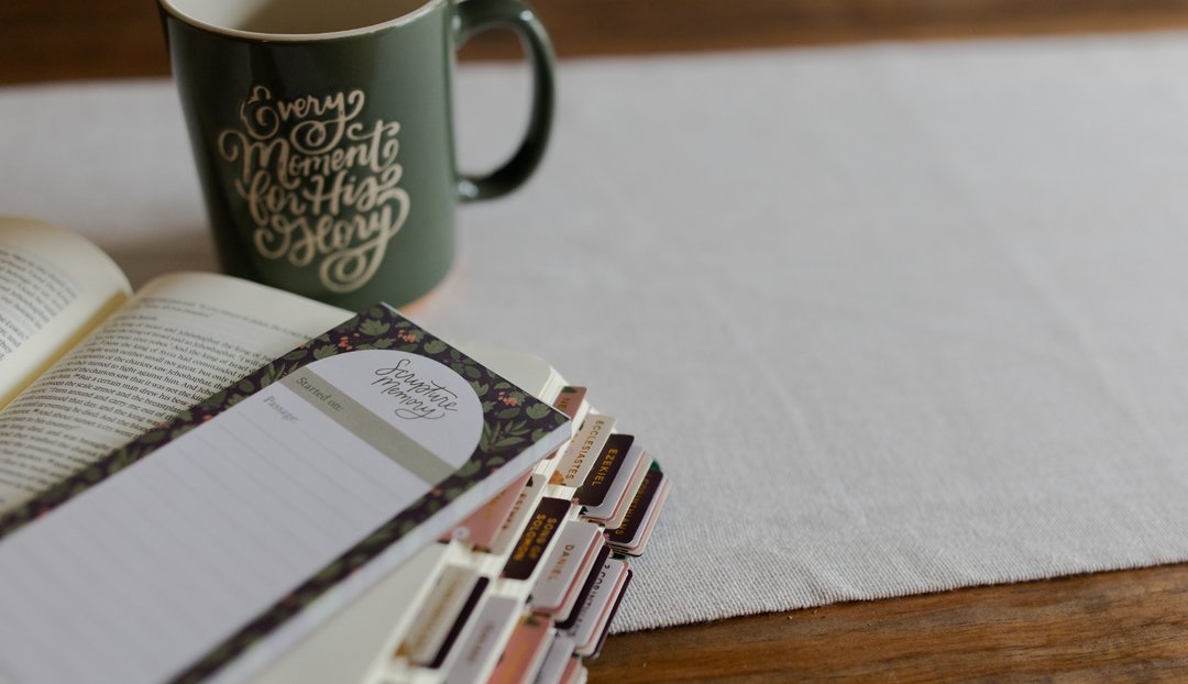 A coffee cup and a notepad on a wooden table and a white table runner