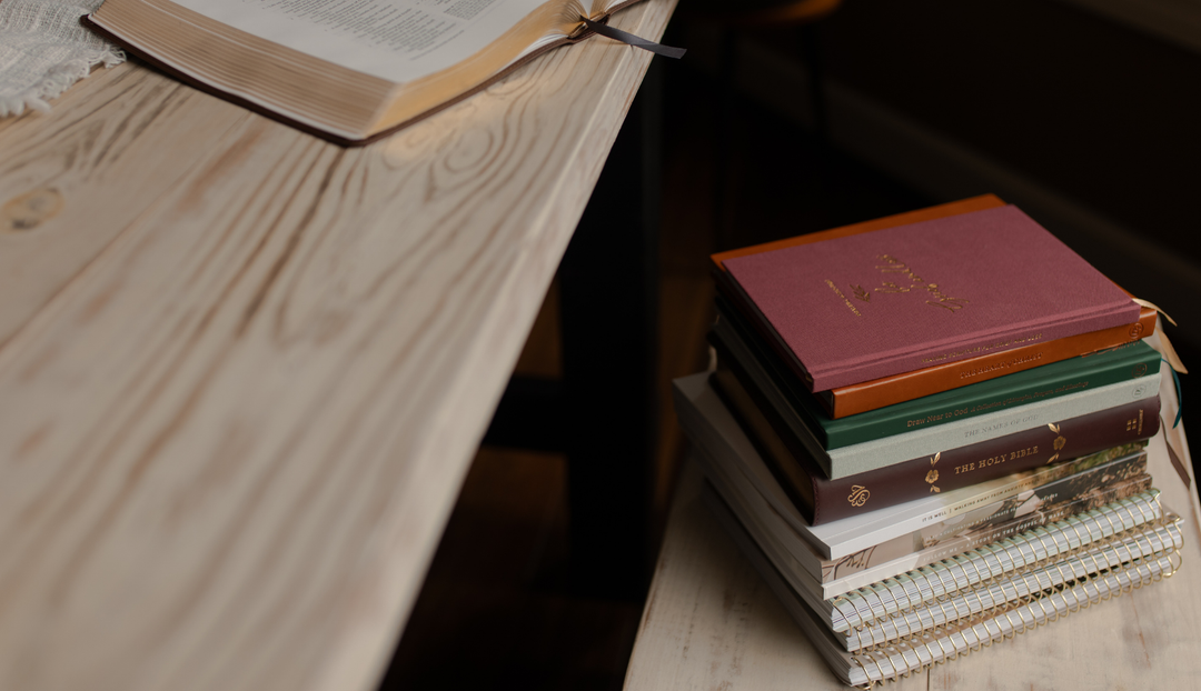 A stack of Daily Grace books on a wooden surface near a wooden table