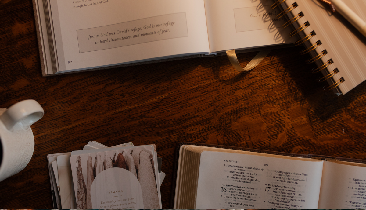 An open bible and study with various accessories on a wooden table