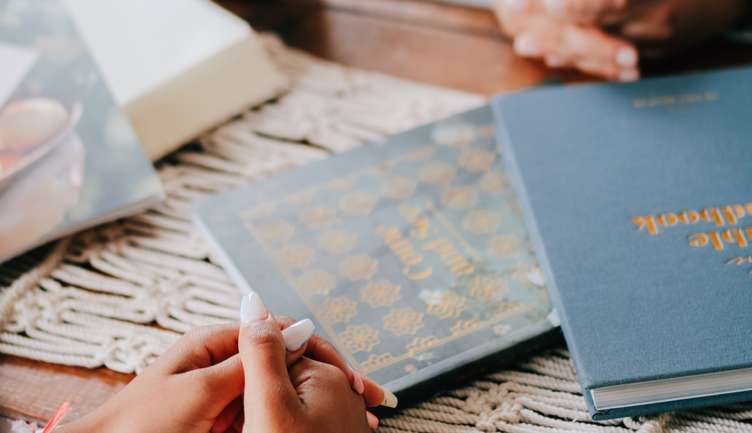 A womans hand resting on a table near some closed daily grace books