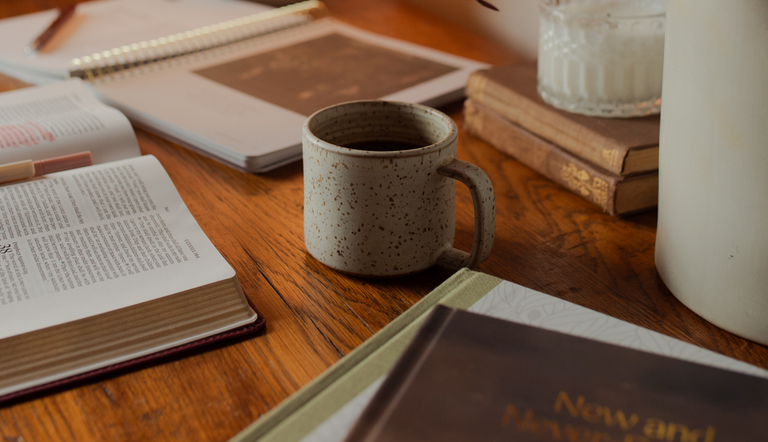 A coffee cup on a wooden table near multiple studies