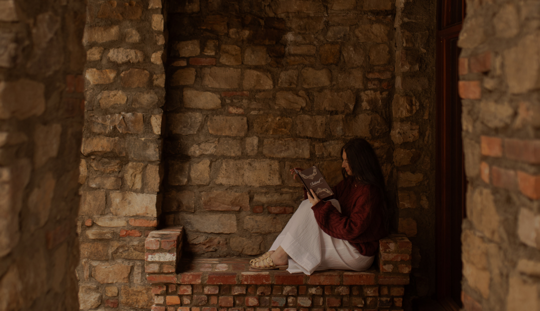 A woman reading a book while sitting on a brick bench near a brick wall