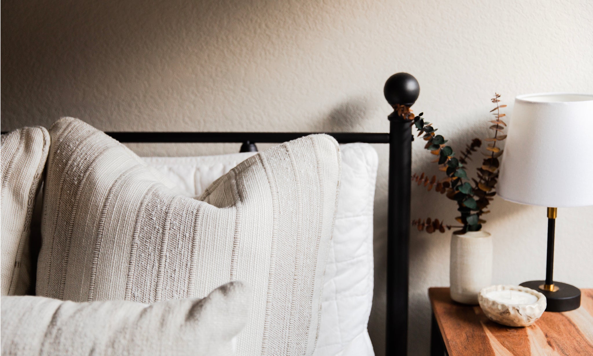 Made bed with white pillows and small lamp on night stand